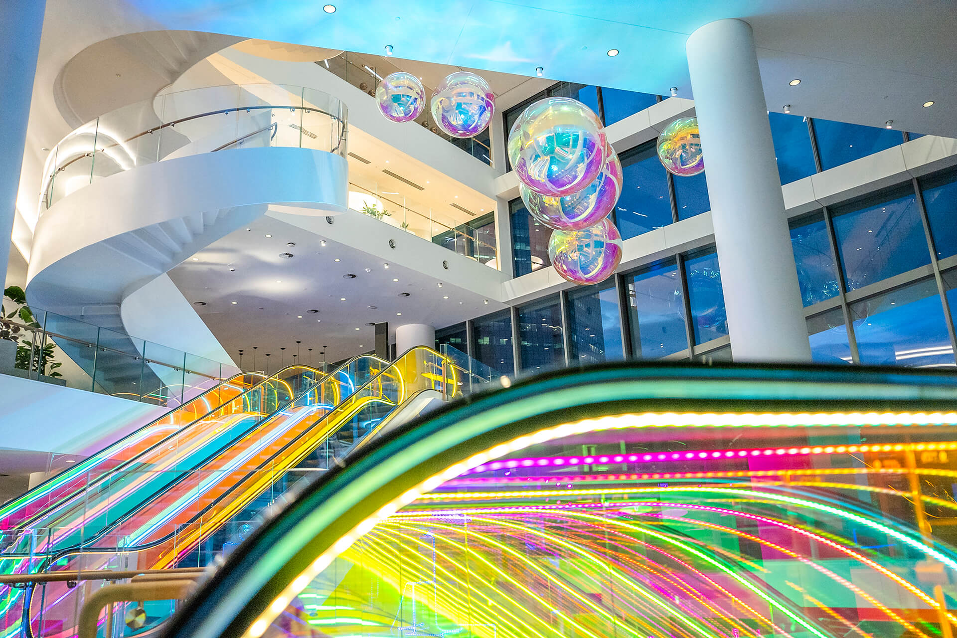 VANDAL Experiential Christmas Campaign for Dexus in the commercial lobby of 50 Bridge Street, Sydney showing dichroic film on escalators and artistic dichroic baubles.