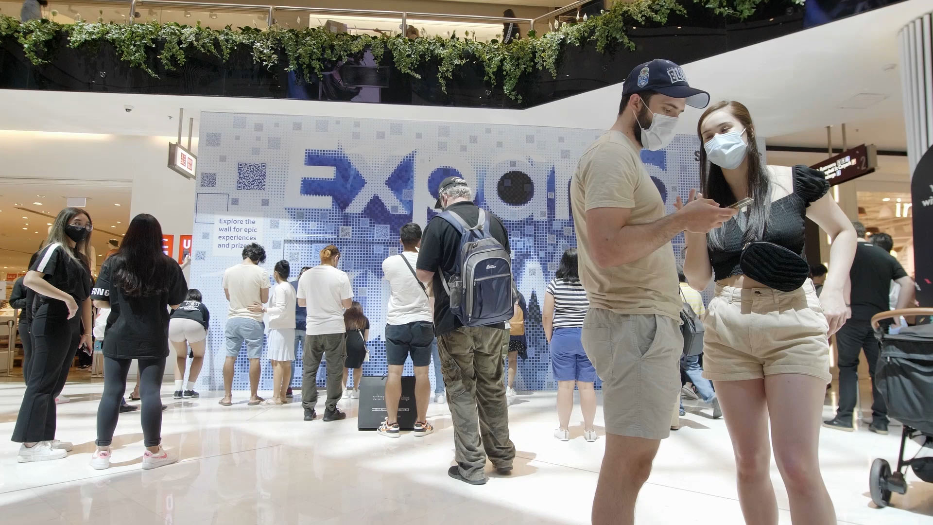 Shoppers interacting with a Sydney based experiential piece for Samsung featuring a mosaic of scannable QR codes that come together to say 'Expand our World'