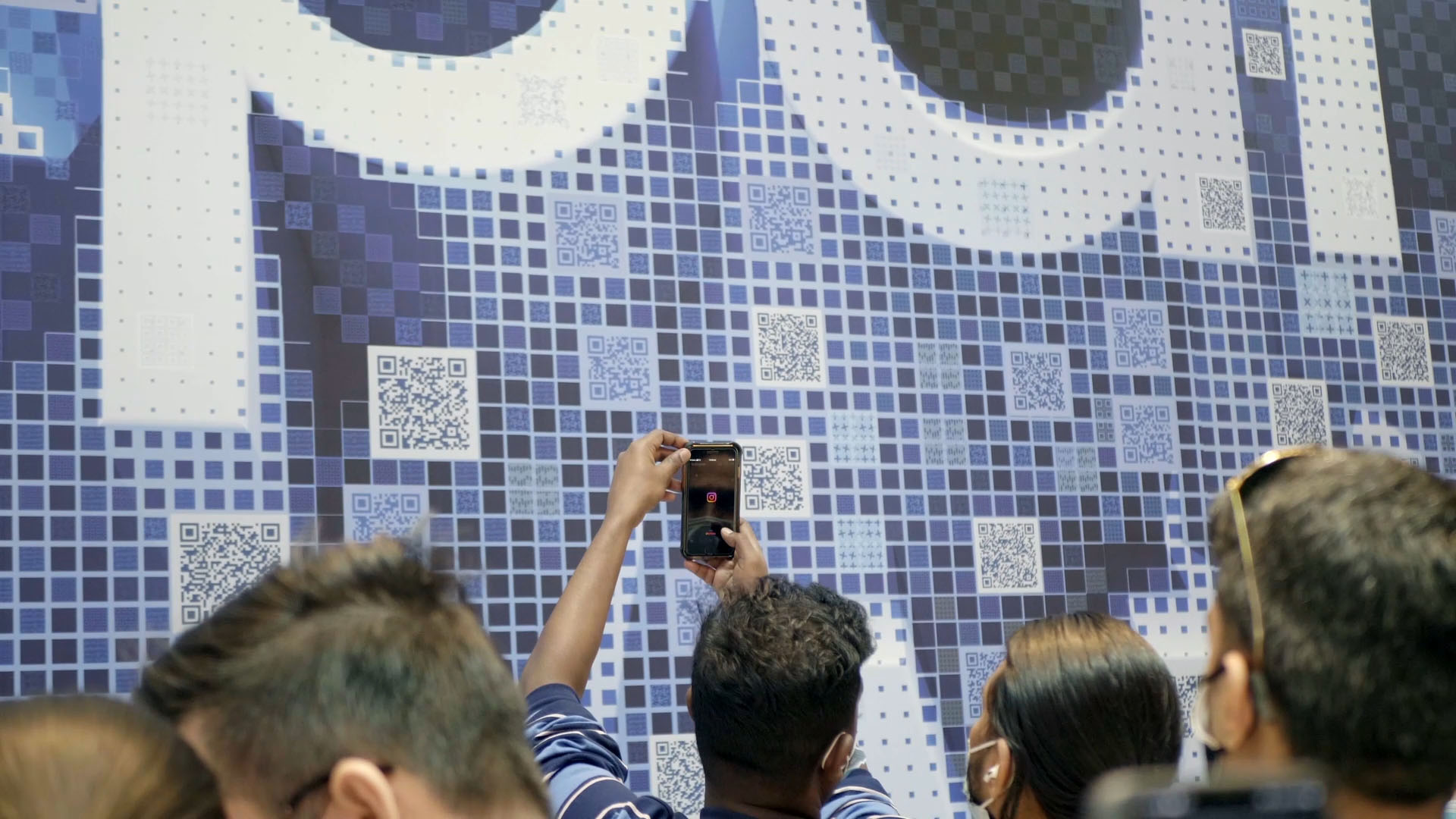 Shoppers interacting with a Sydney based experiential piece for Samsung featuring a mosaic of scannable QR codes that come together to say 'Expand our World'