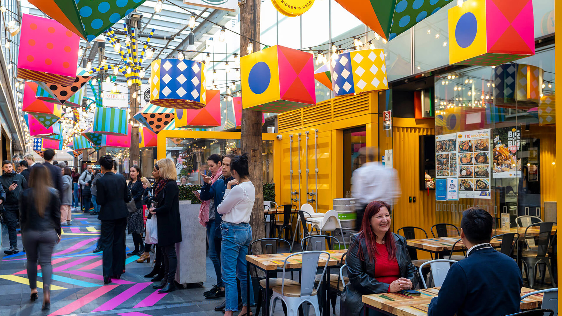 Shoppers enjoying a multicoloured placemaking artistic mural at World Square - a World of Colour by VANDAL