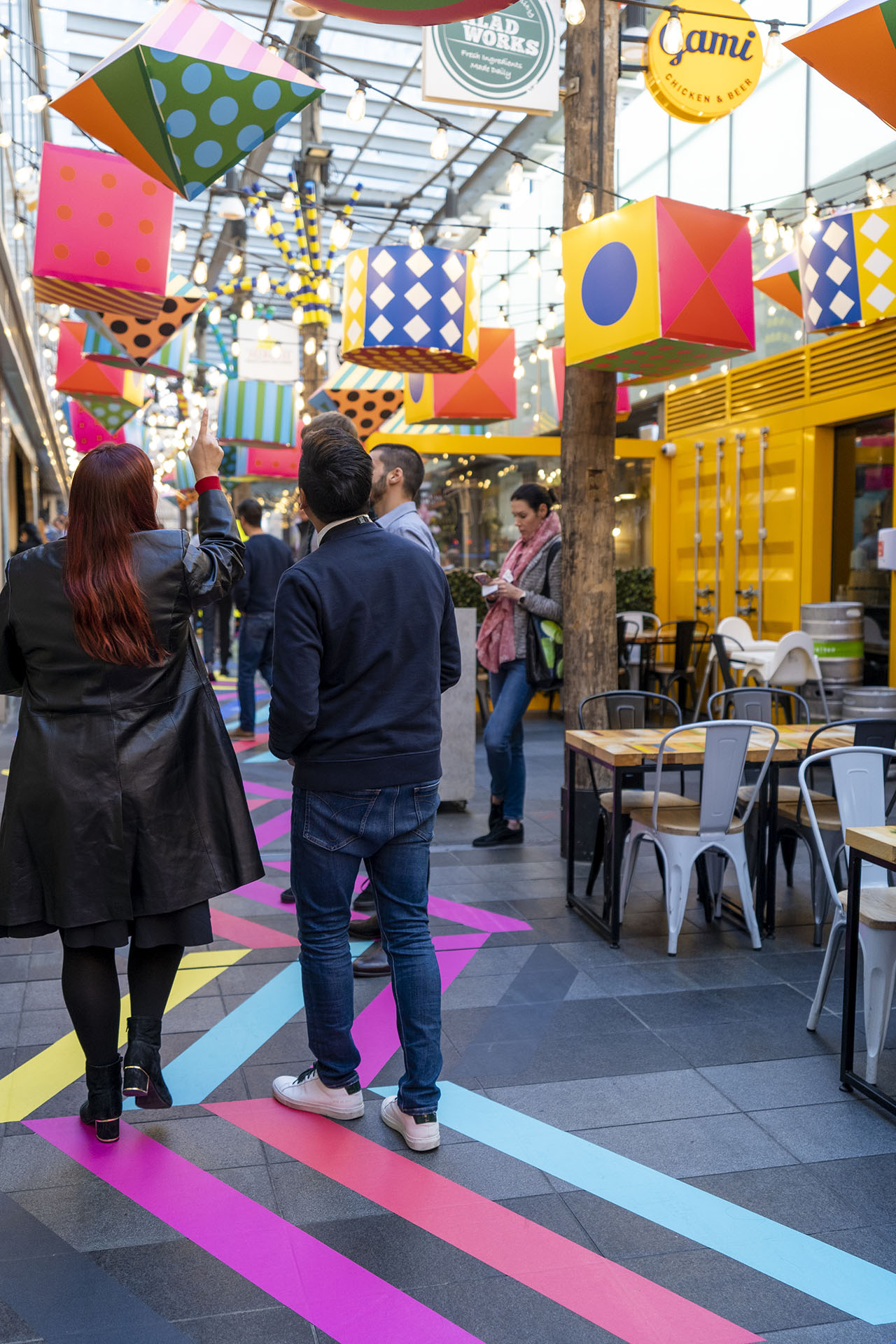 Shoppers enjoying a multicoloured placemaking artistic mural at World Square - a World of Colour by VANDAL