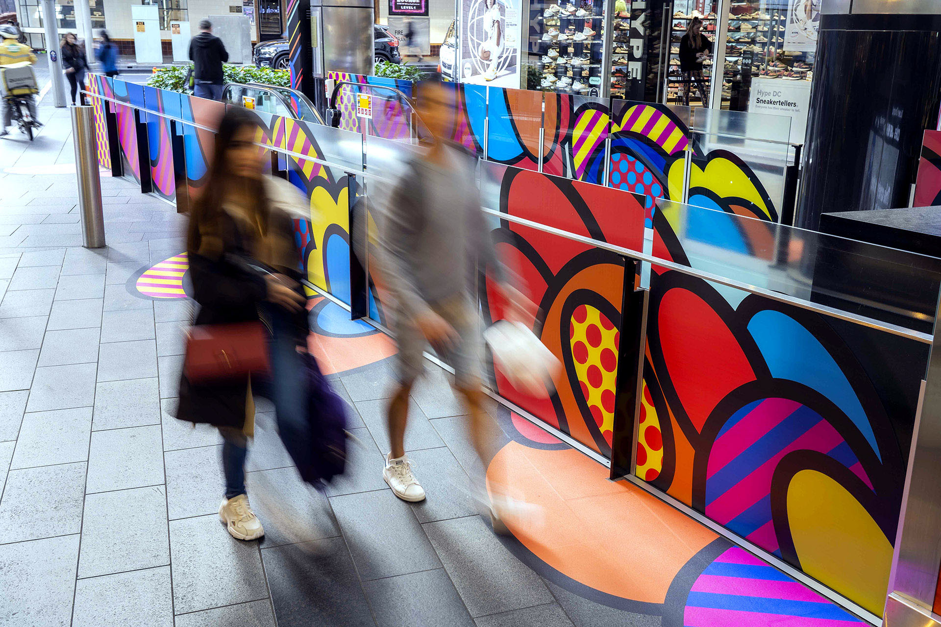 Shoppers enjoying a multicoloured placemaking artistic mural at World Square - a World of Colour by VANDAL