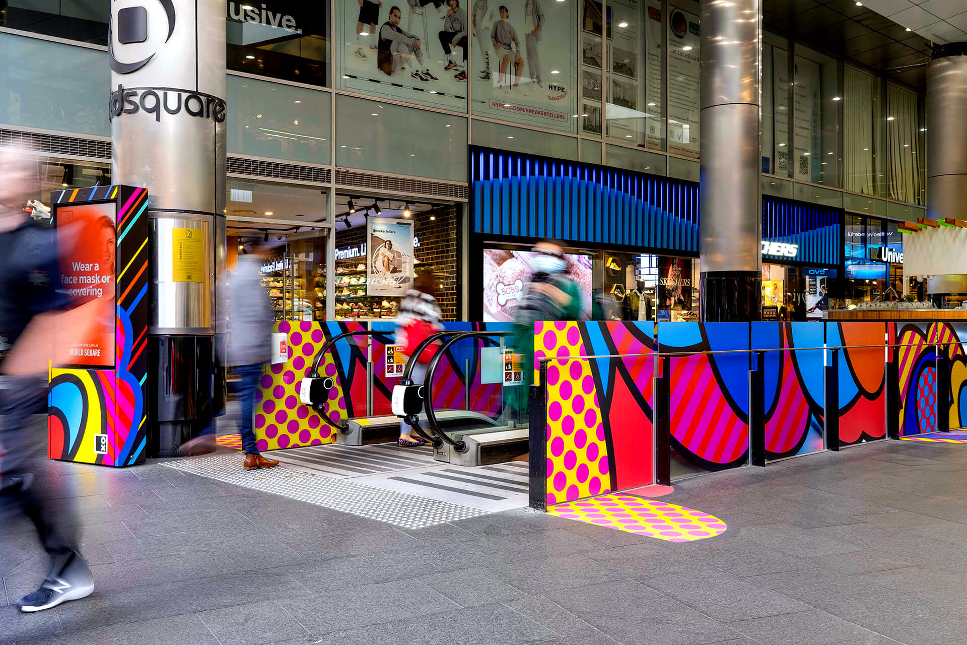 Shoppers enjoying a multicoloured placemaking artistic mural at World Square - a World of Colour by VANDAL