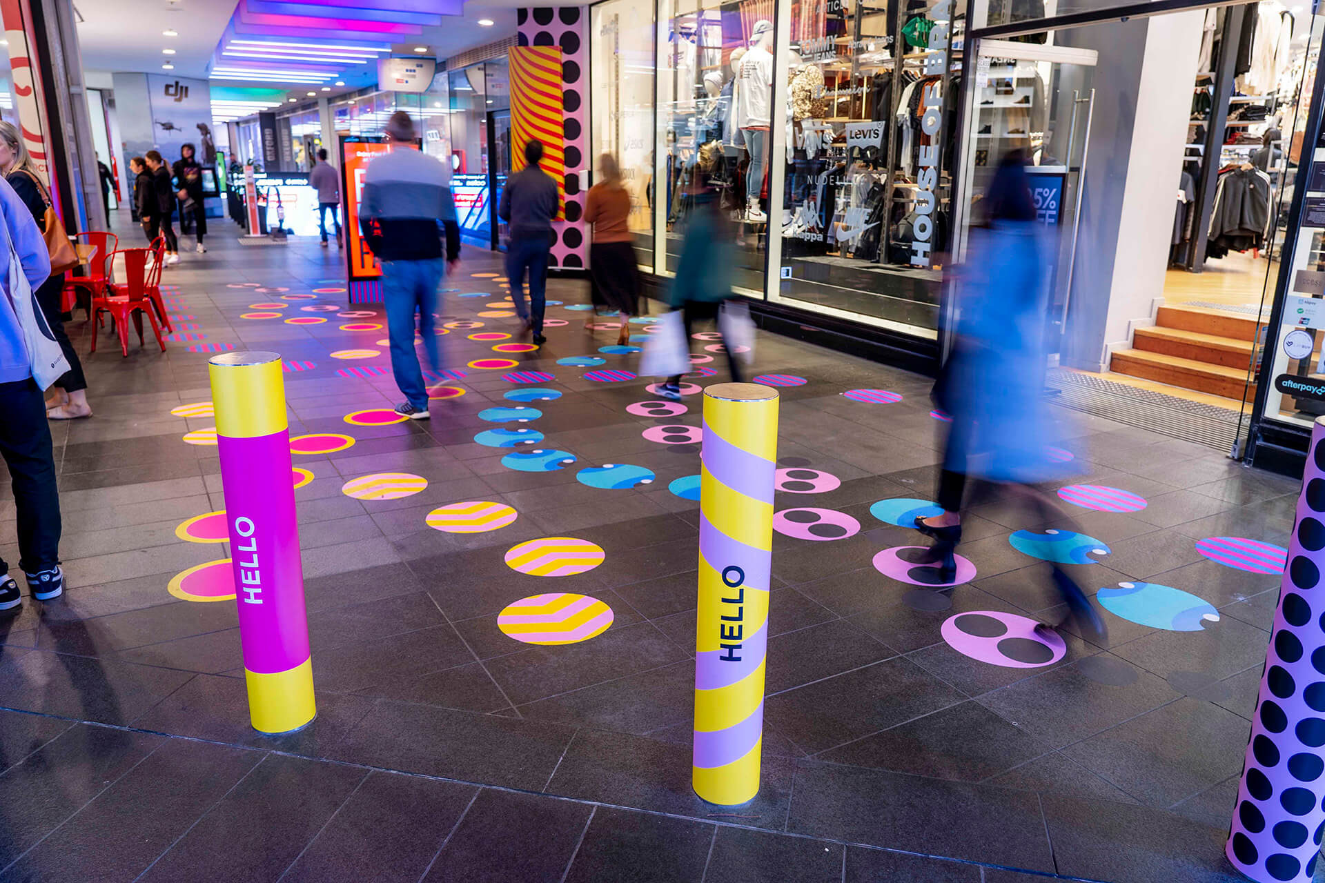 Shoppers enjoying a multicoloured placemaking artistic mural at World Square - a World of Colour by VANDAL