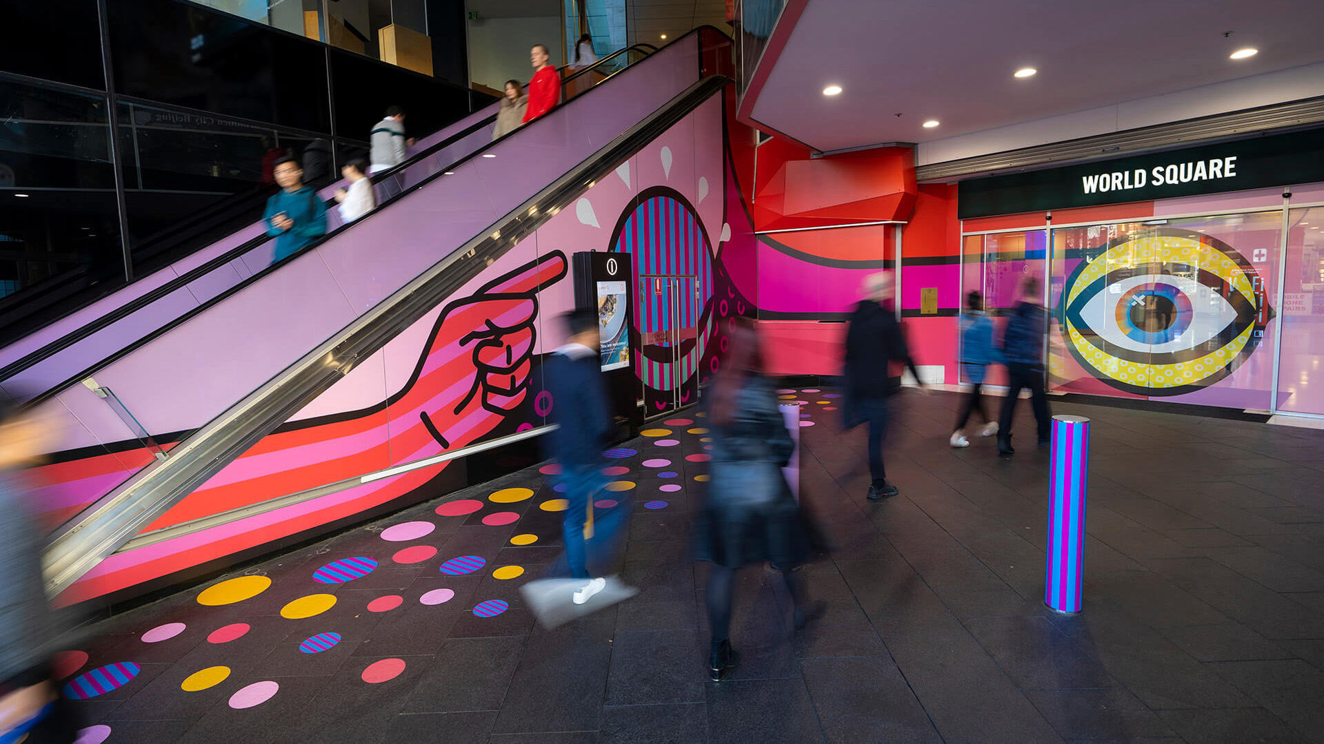 Shoppers enjoying a multicoloured placemaking artistic mural at World Square - a World of Colour by VANDAL