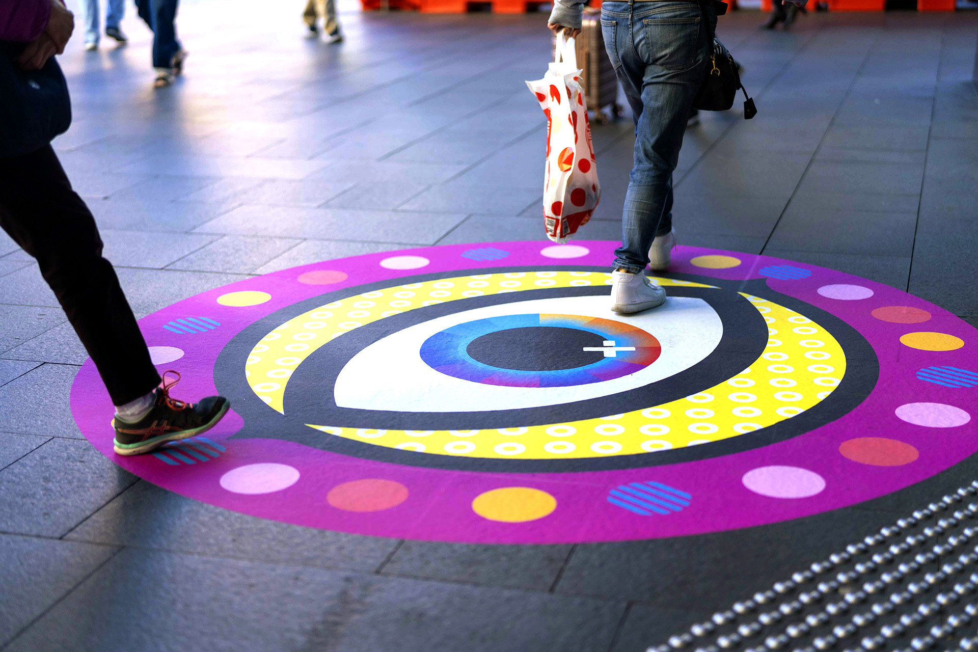 Shoppers enjoying a multicoloured placemaking artistic mural at World Square - a World of Colour by VANDAL