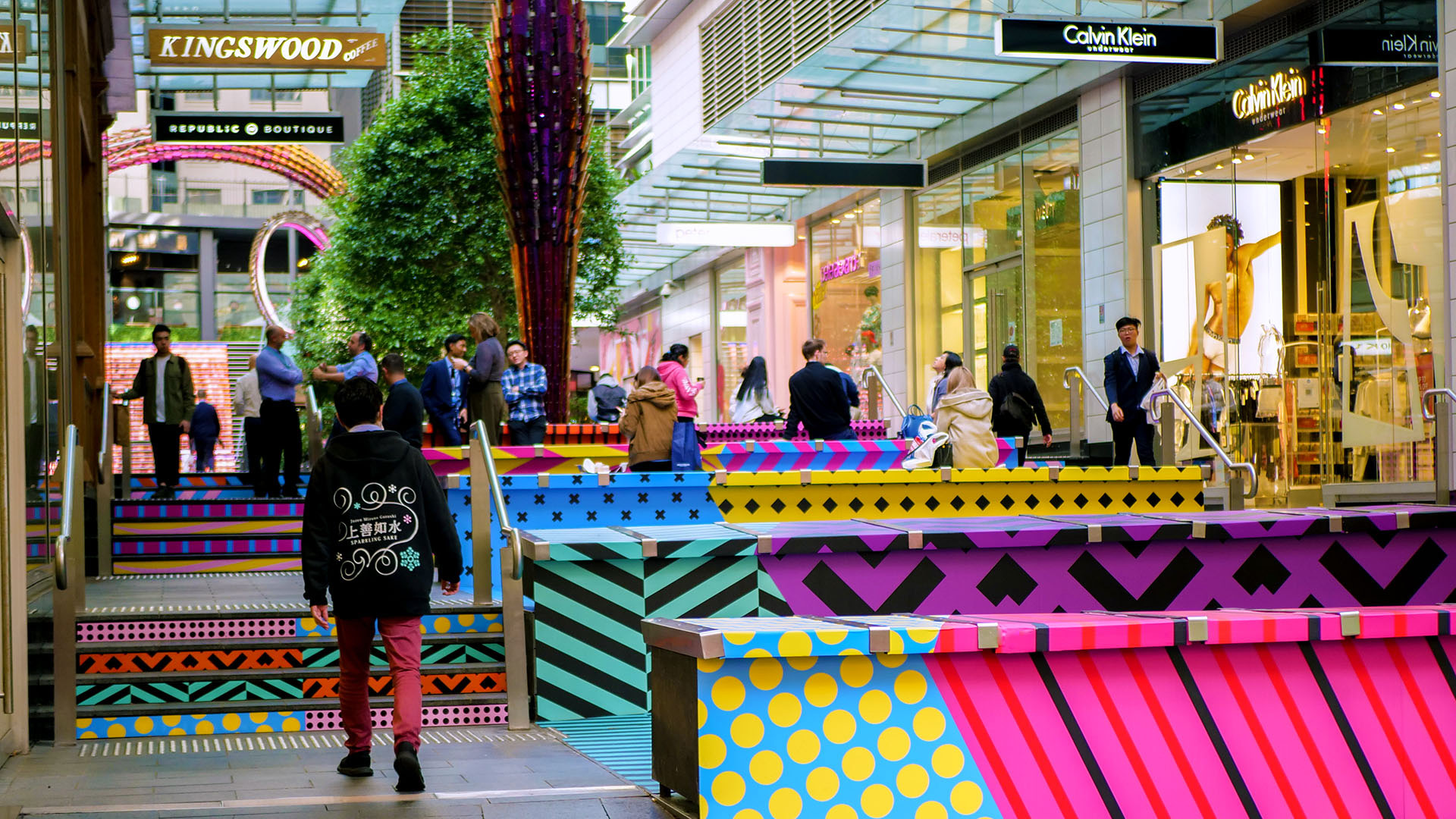 Shoppers enjoying a multicoloured placemaking artistic mural at World Square - a World of Colour by VANDAL