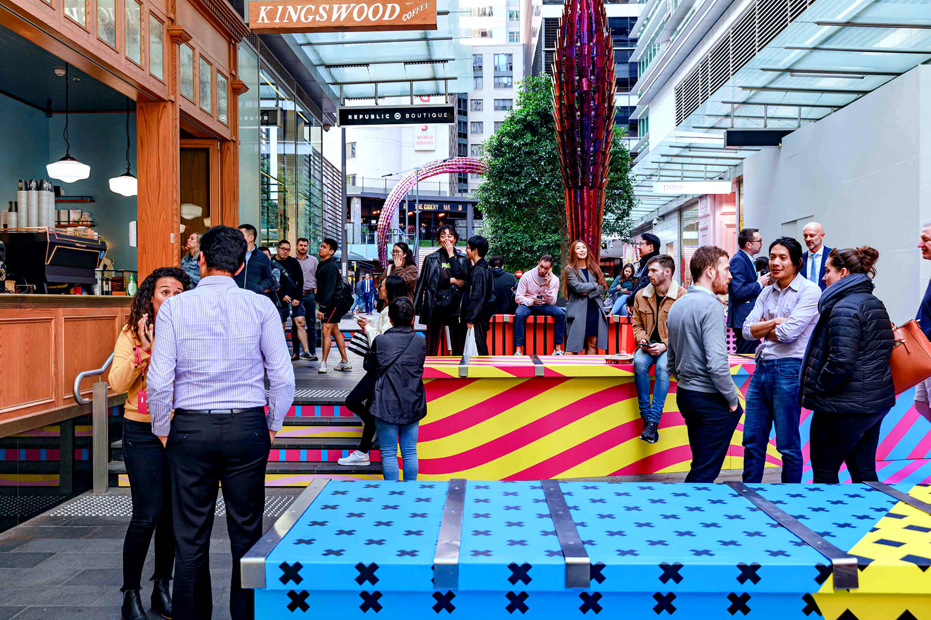 Shoppers enjoying a multicoloured placemaking artistic mural at World Square - a World of Colour by VANDAL