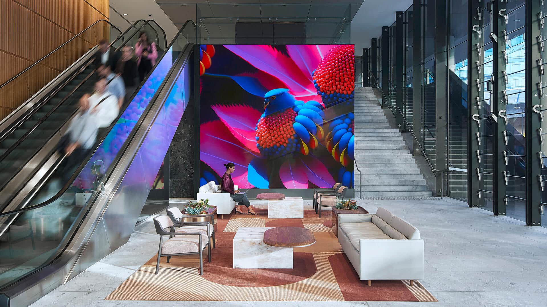 People using an escalator that runs adjacent to a large scale AI generated artwork depicting the Natural Rhythms of Australia.